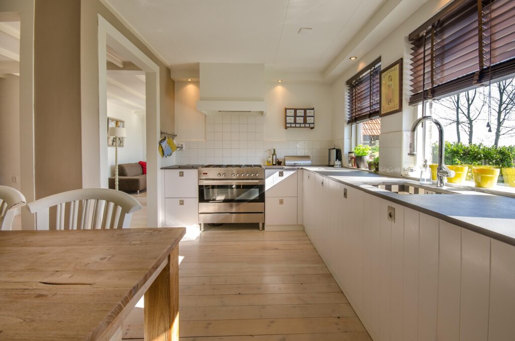 A finished residential renovation showing a modern island kitchen flowing into a bright dining space, showcasing a total interior reconfiguration.